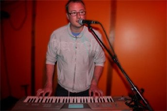 Singer Songwriter playiing keyboards and singing into a microphone
